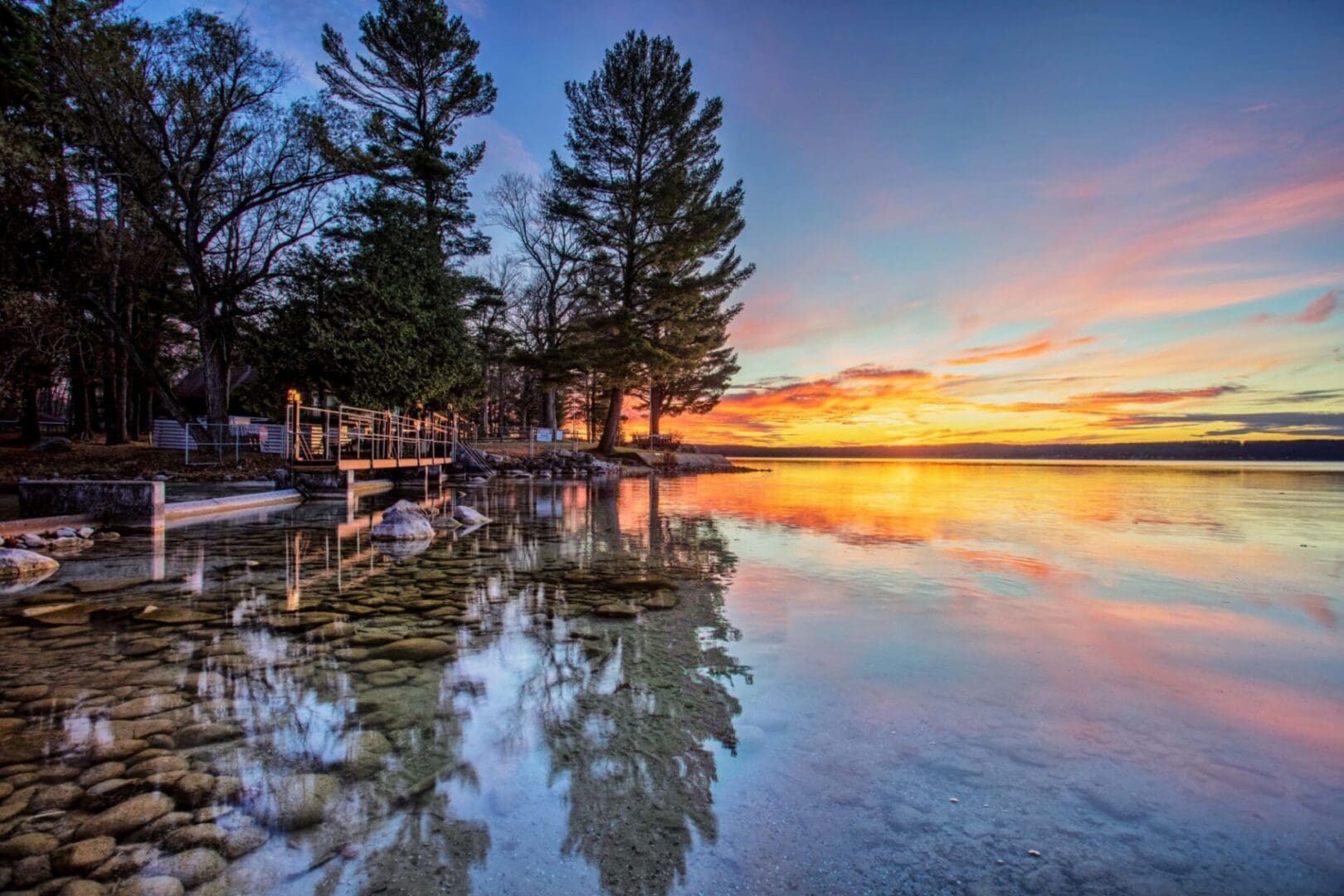 Sunset over a tranquil lakeside scene.